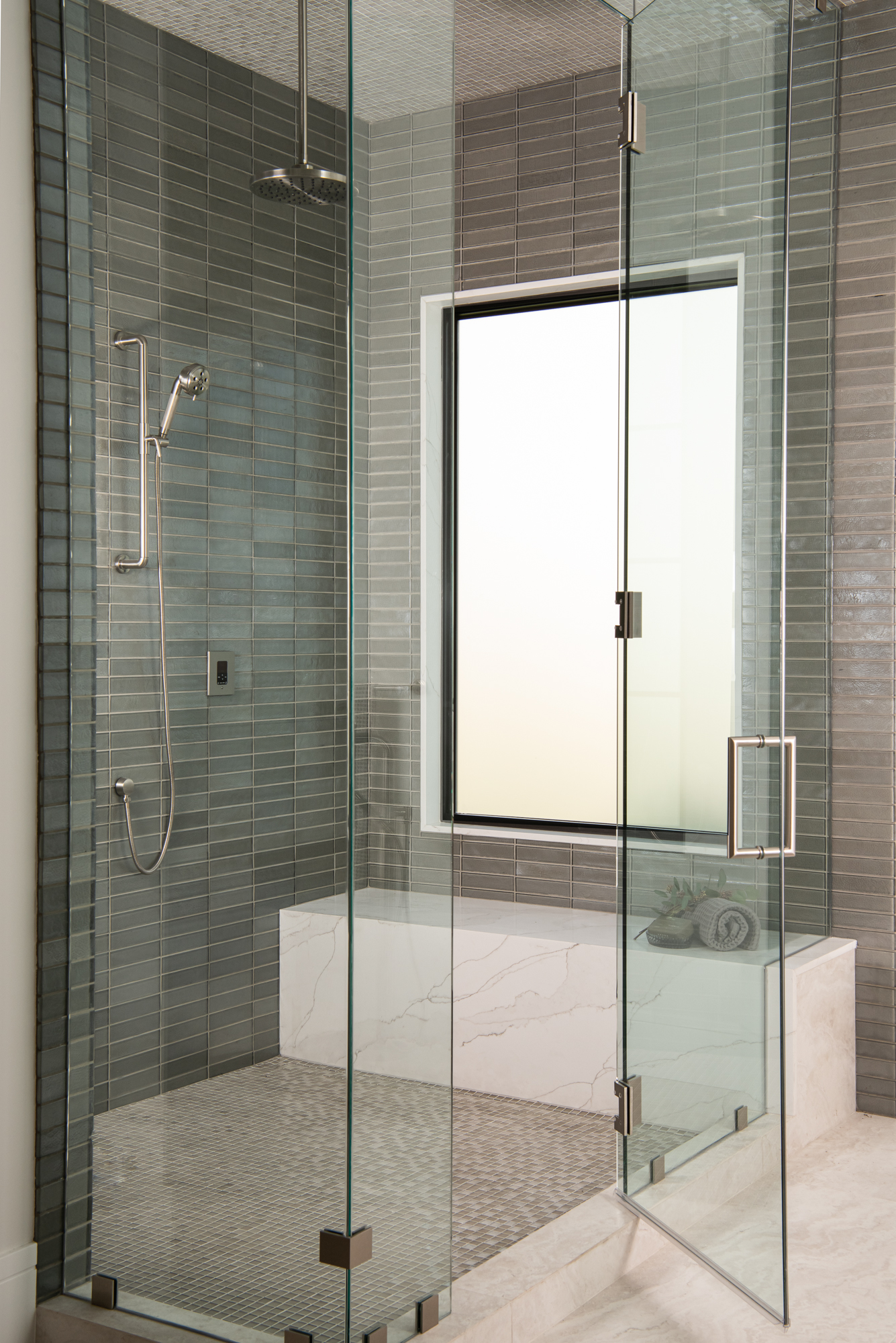 Shower interior with gray vertical stack-bond tile and marble bench