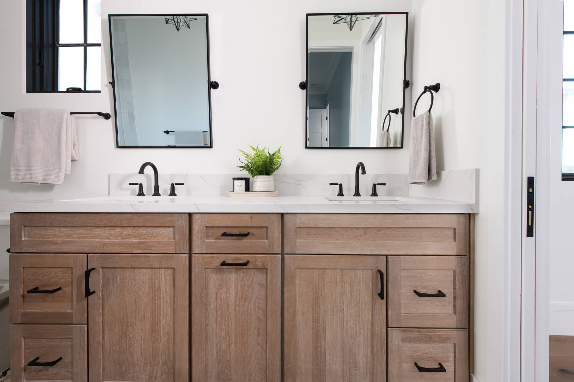 Double vanity straight-on with two black pivot mirrors and fern