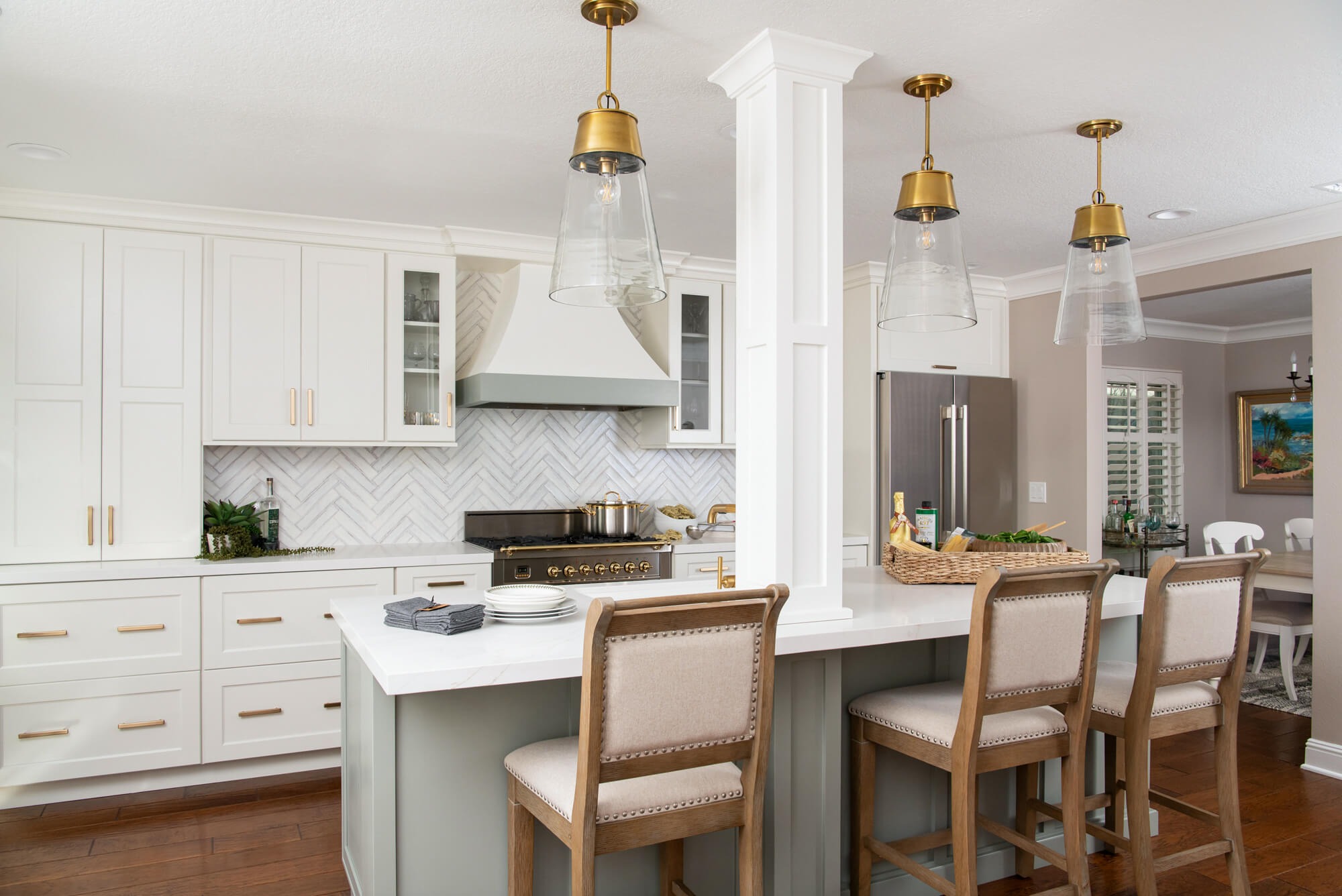 Kitchen with sage island and brass pendants alt angle