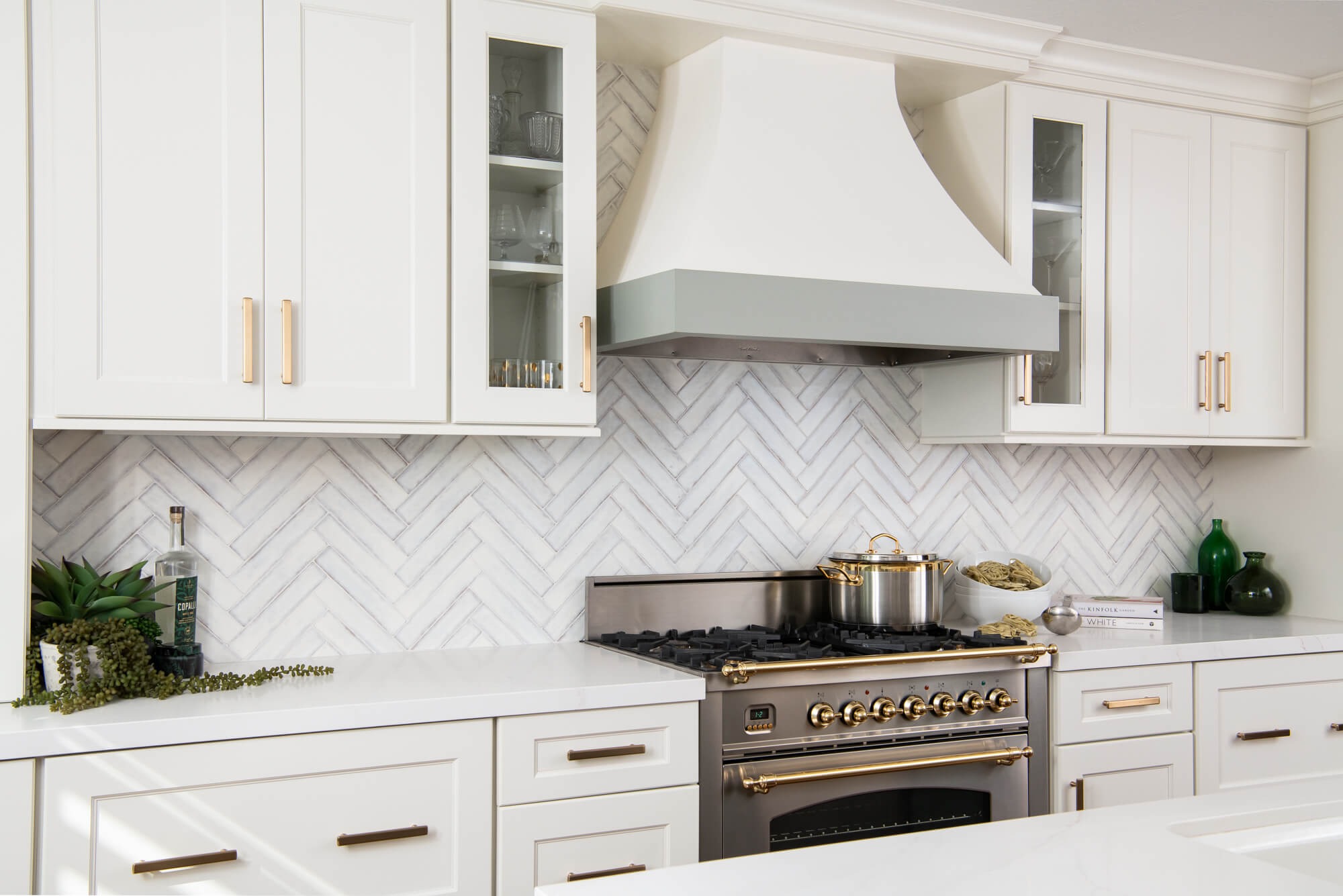 Plaster range hood with herringbone marble backsplash and Ilve range