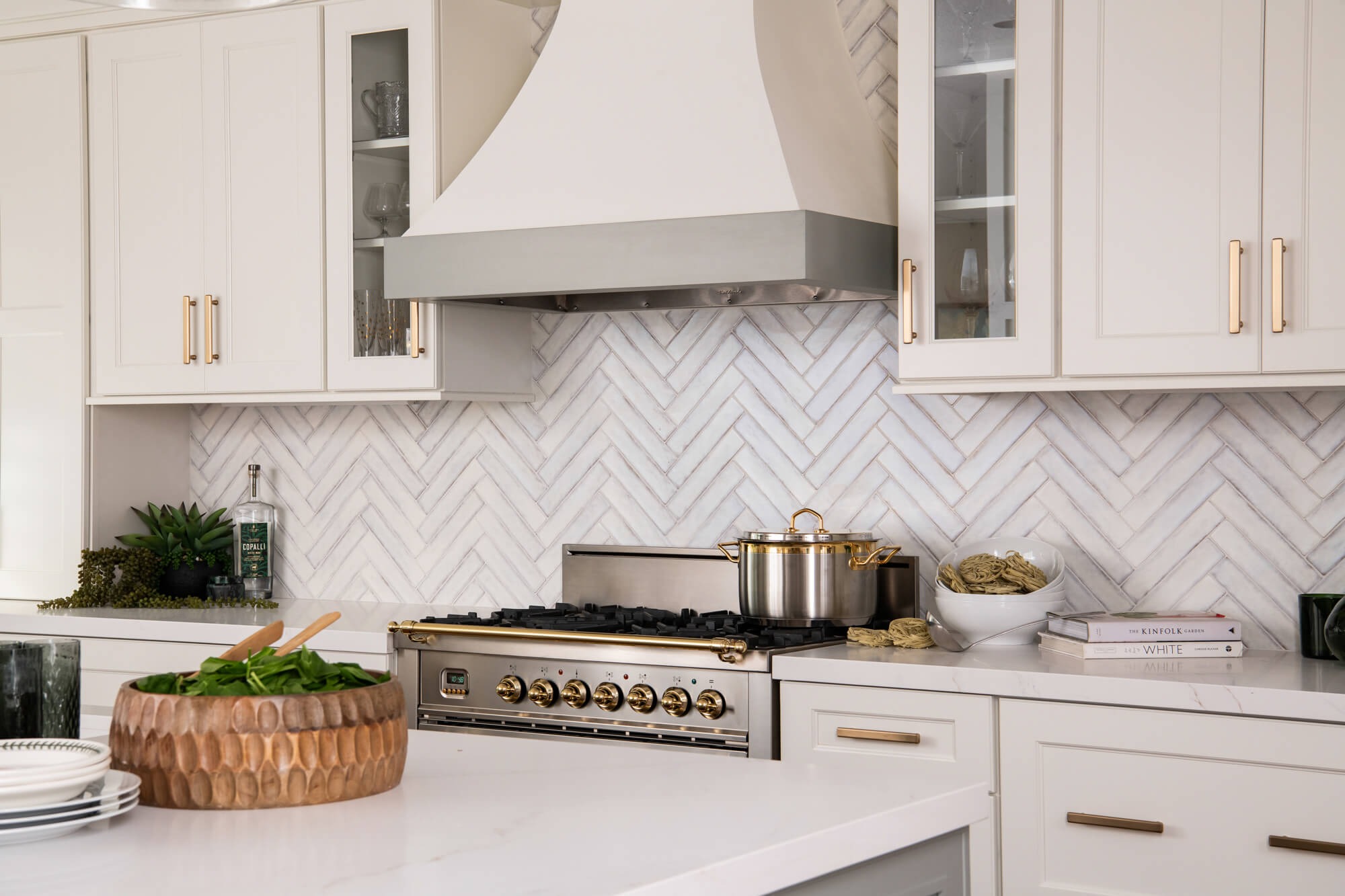 Close detail of herringbone backsplash and gold-trim range