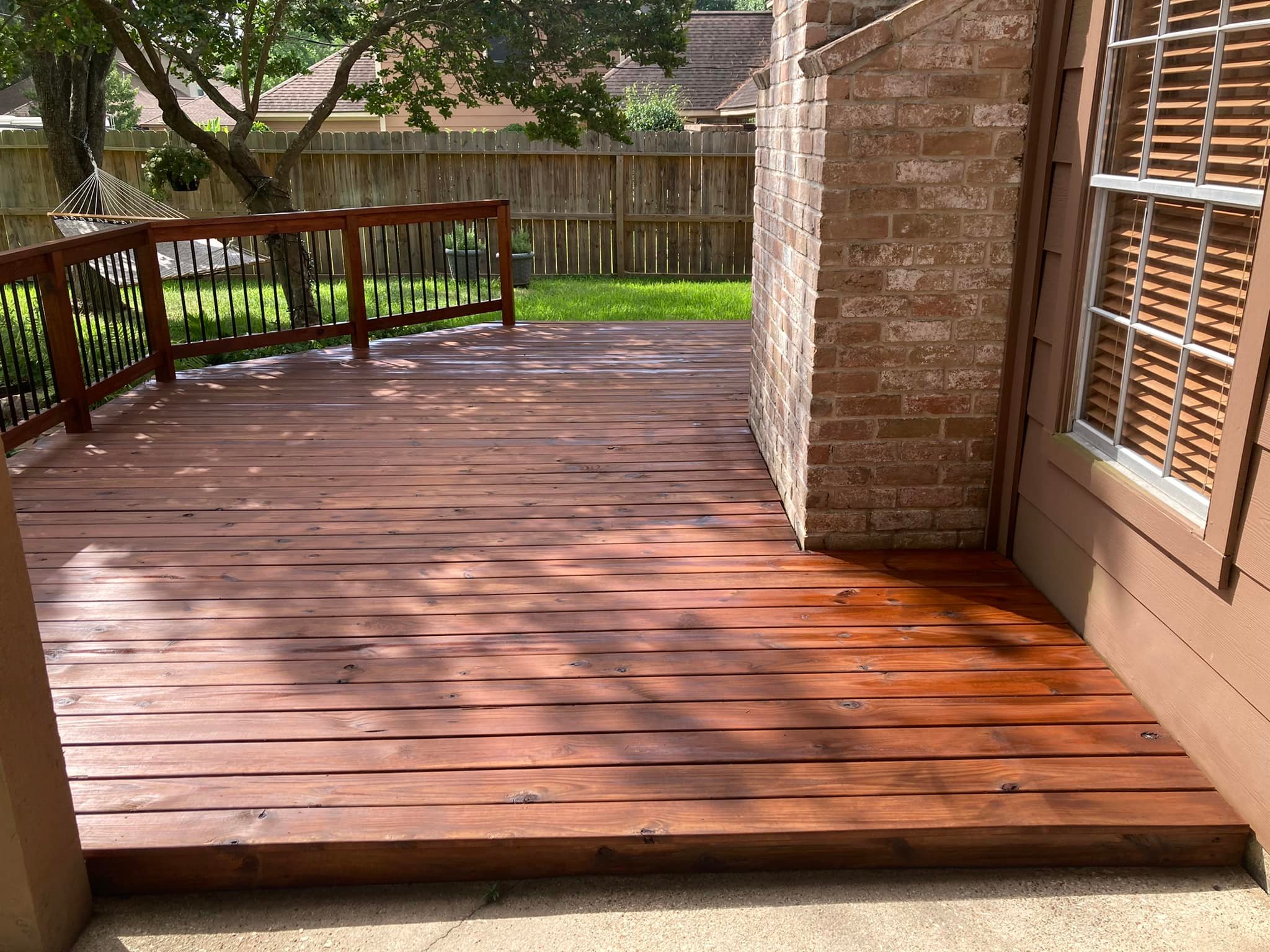 Black and wood deck with vertical balusters and stairs to a dark exterior home