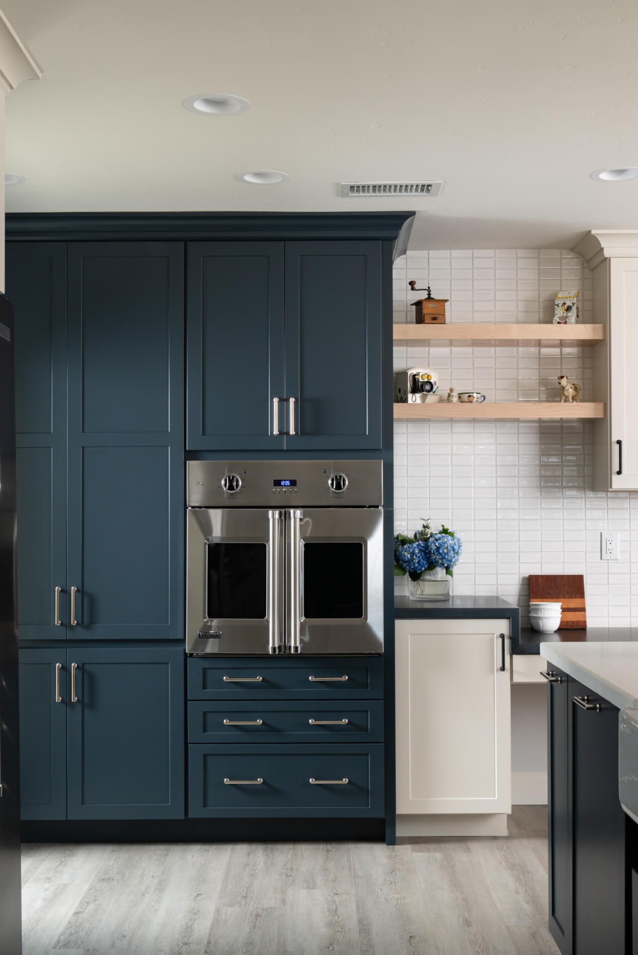 Custom navy built-in cabinet stack with French-door wall oven and floating maple shelves