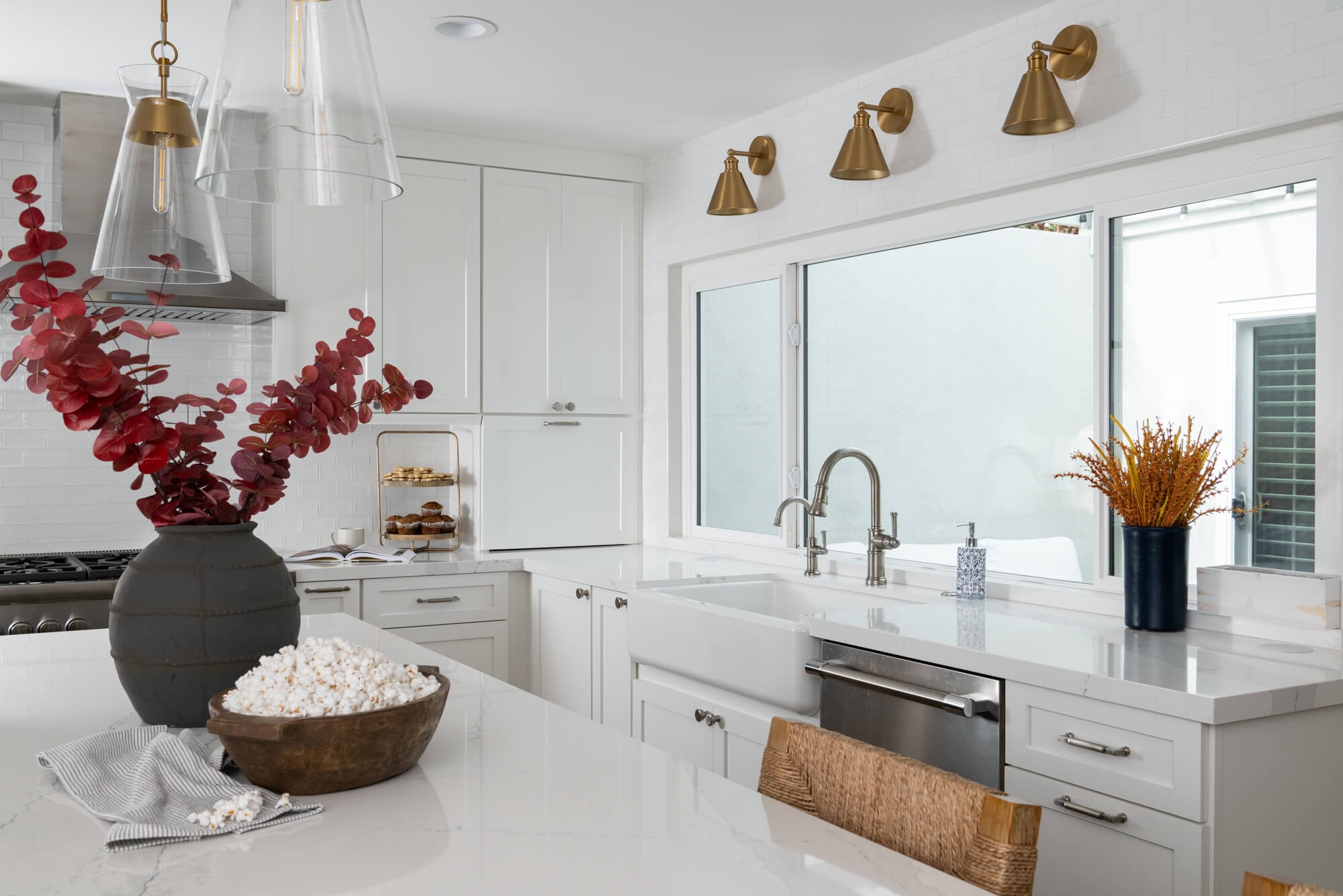 Farmhouse sink with brass triple sconces and dried orange grasses