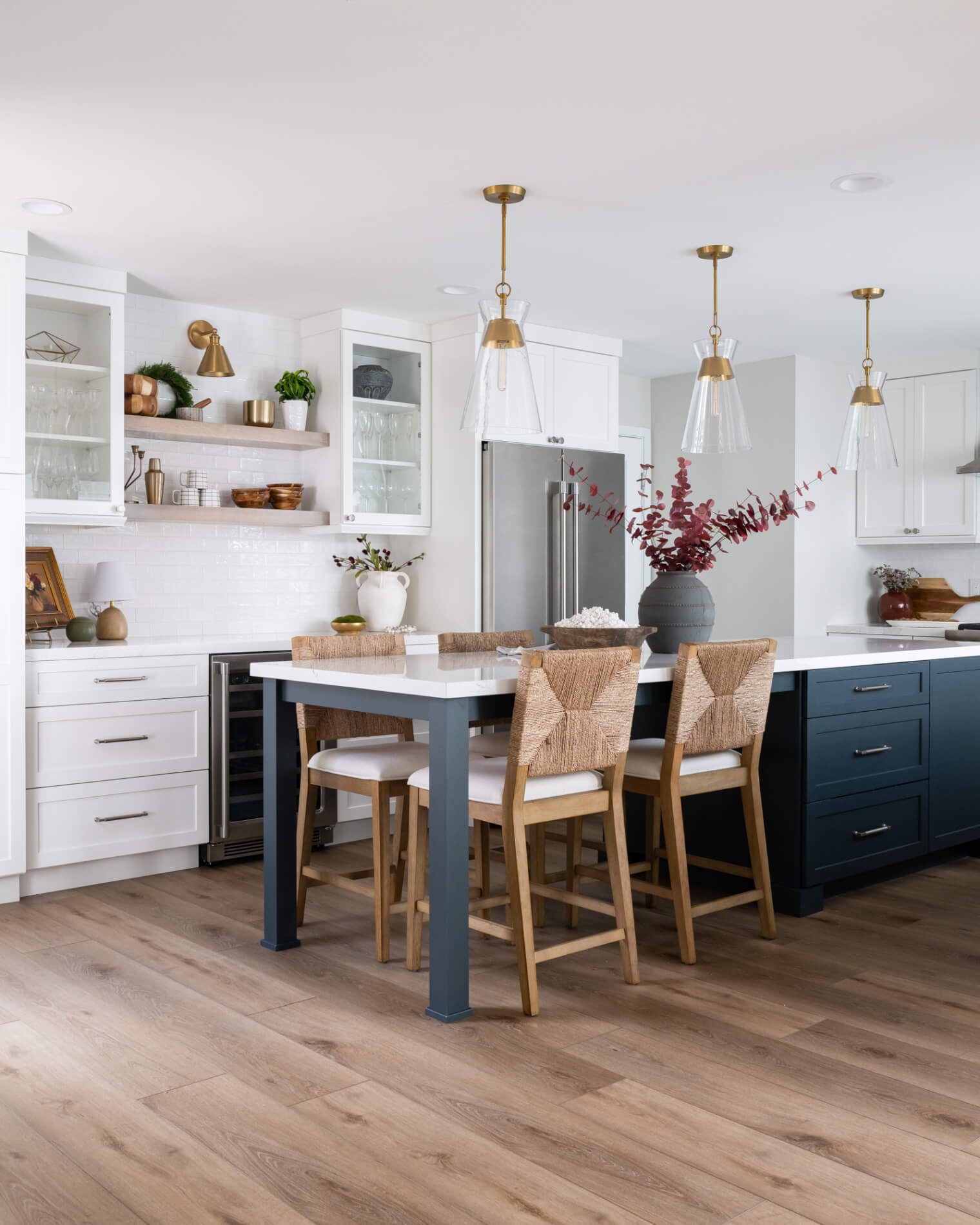Navy peninsula island with three rope-back stools and marble waterfall
