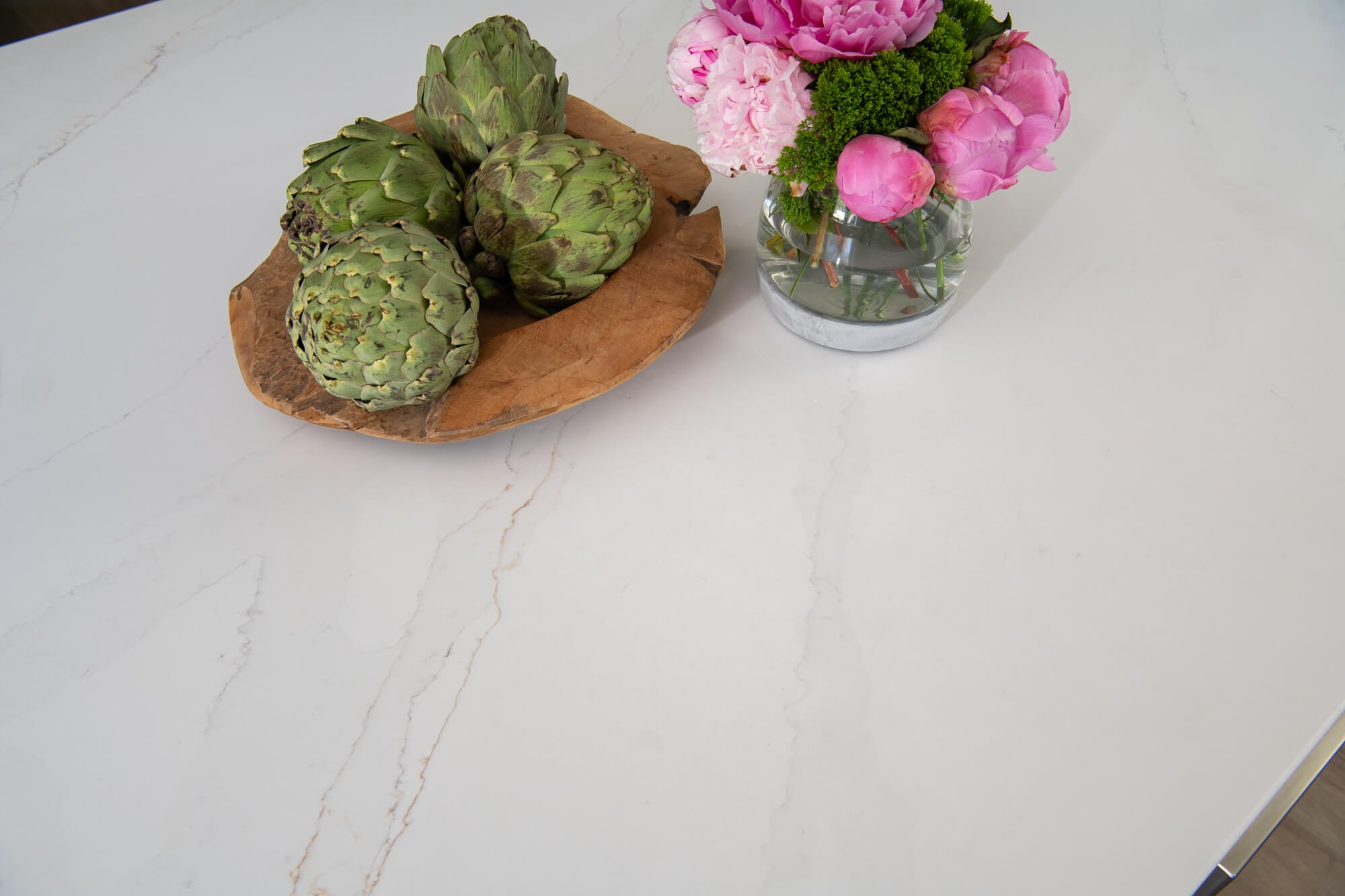 Marble counter close-up with artichokes and peonies in Cumming kitchen
