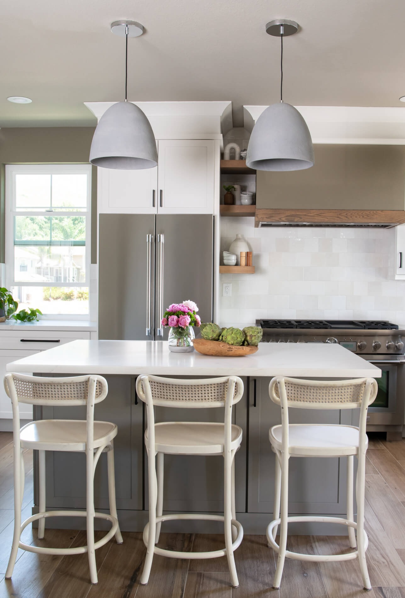 Island with three cane stools and grey dome pendants
