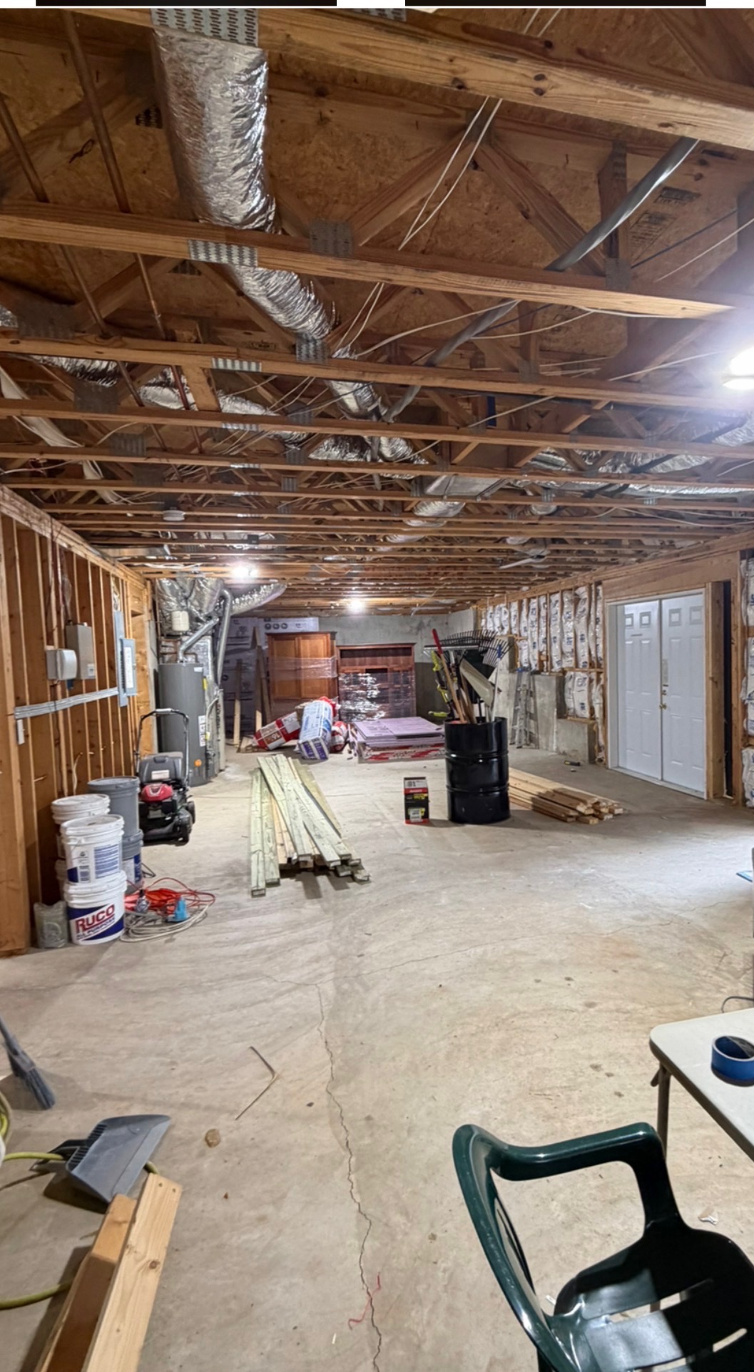 Unfinished basement before remodel with exposed studs, HVAC, and storage
